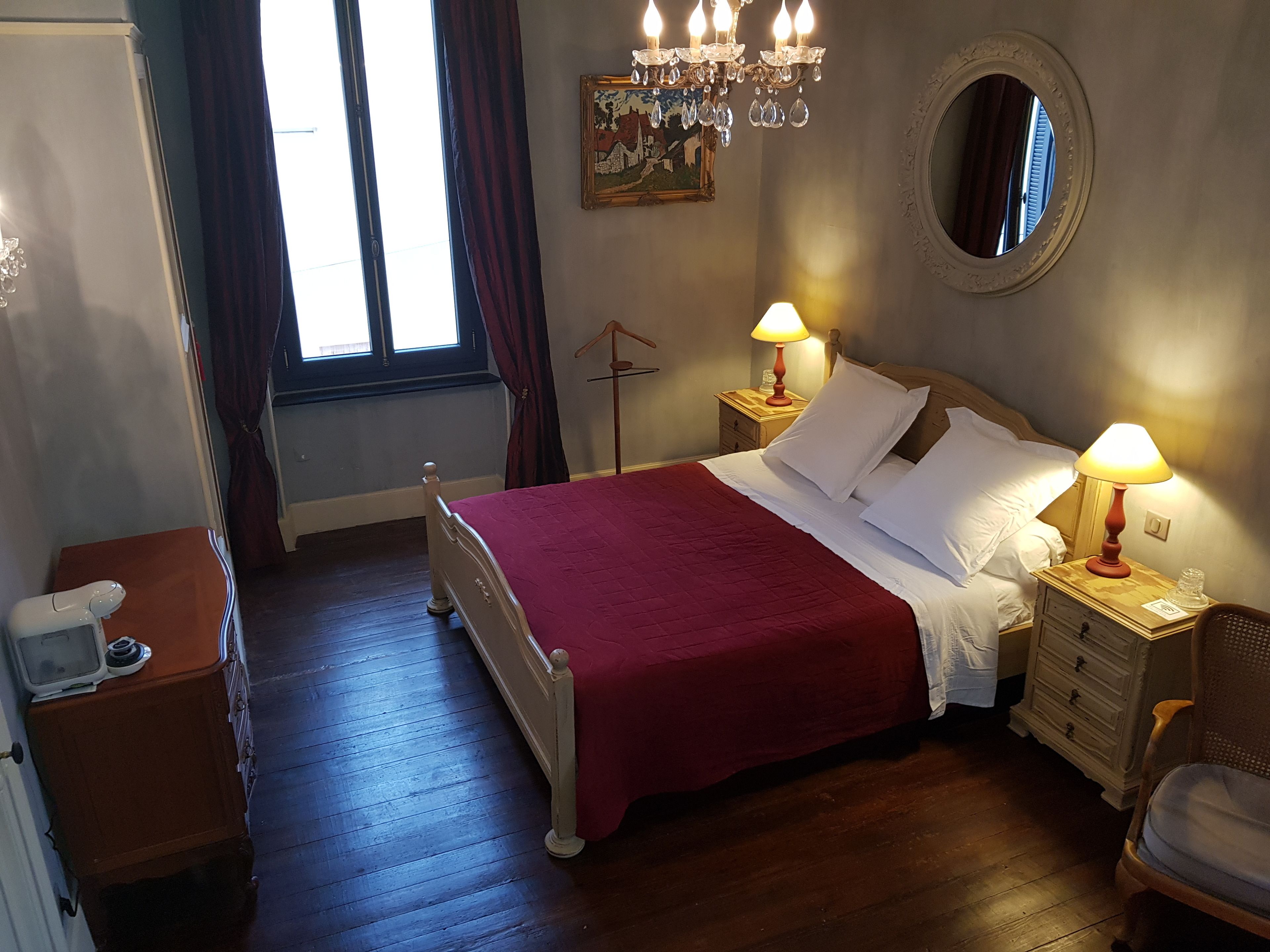 Een keurig opgemaakte slaapkamer met een houten bed, twee nachtkastjes met lampen, een kaptafel en een spiegel aan de muur.