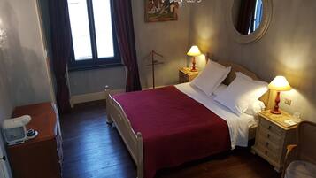 Een keurig opgemaakte slaapkamer met een houten bed, twee nachtkastjes met lampen, een kaptafel en een spiegel aan de muur.