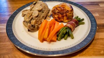 A plate with a piece of meat, a baked item, and vegetables.