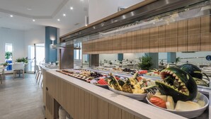 A buffet with a variety of fruits and vegetables, a wooden counter, and a modern interior with a glass partition. - Aparthotel Esquinzo Y Monte Del Mar (Pajara)