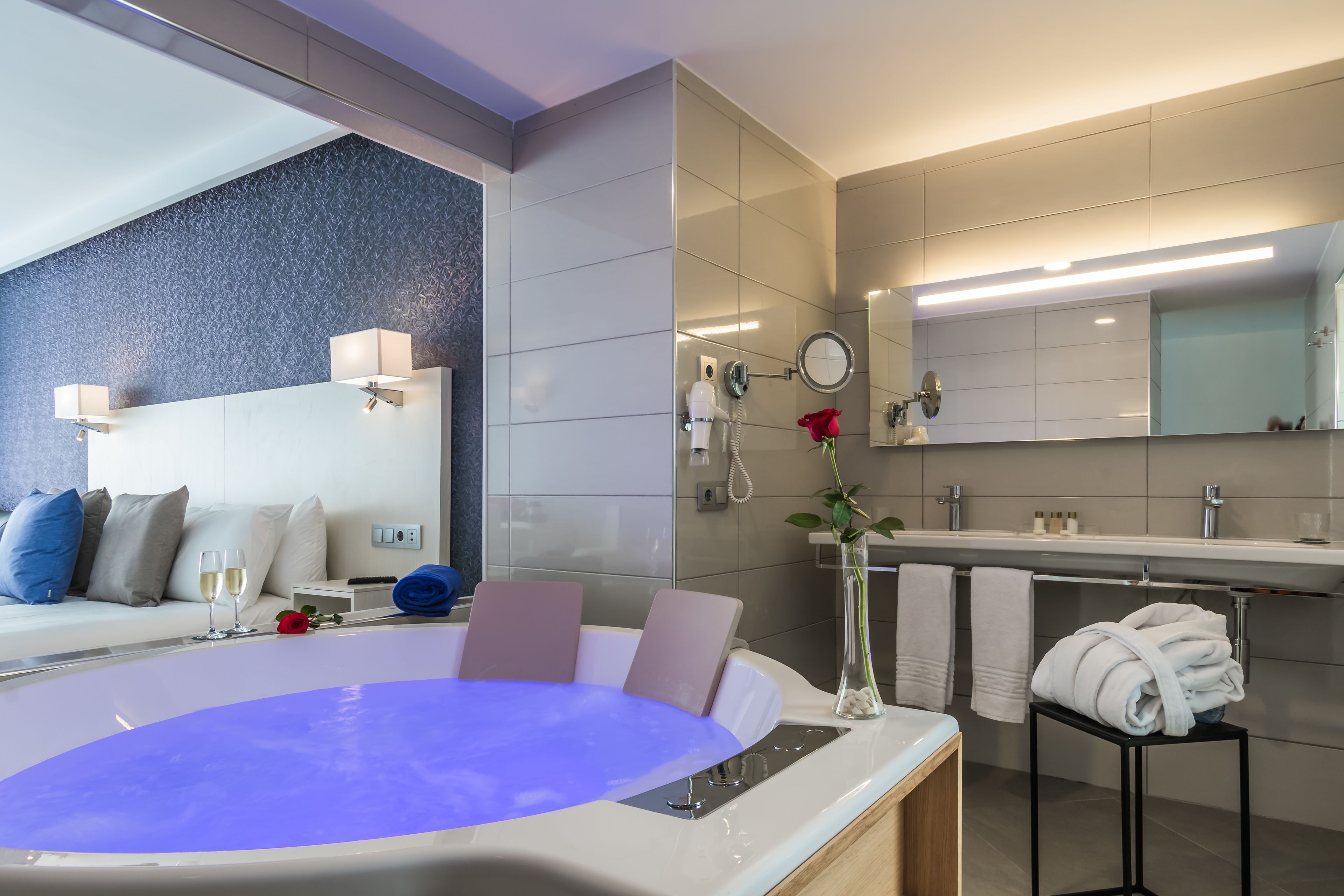 A modern bathroom with a bathtub, a vanity with a mirror, and a towel rack.