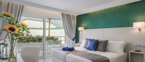Una habitación de hotel moderna con una cama, mesitas de noche, un escritorio con una silla y vistas al exterior a través de una puerta corrediza de vidrio.