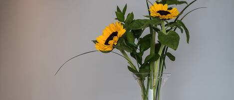 A dining table with a vase of sunflowers, a glass, and a bottle.