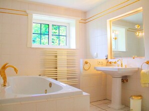 Ein Badezimmer mit Badewanne, Waschbecken, Spiegel und Fenster.