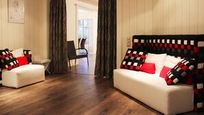 Een kamer met twee witte banken, waarvan er een voorzien is van decoratieve kussens, en een houten vloer.