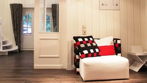 Een slaapkamer met een bed, nachtkastje, raam met gordijnen en een aan de muur hangend schilderij.
