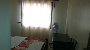 Una stanza piccola e poco illuminata, con un letto, una scrivania e una sedia.