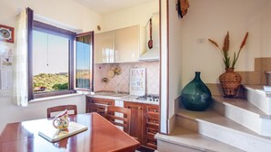 A kitchen with wooden cabinets, a window with a view, a dining table with chairs, and a vase on the counter. - Gorgeous home in Petrizzi with house sea view (Petrizzi)