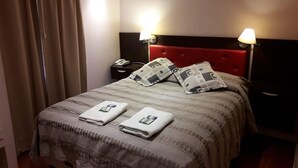 A hotel room with a bed, two bedside lamps, a nightstand, and a window with curtains. - ElMaima Hotel (Veintiocho de Noviembre)