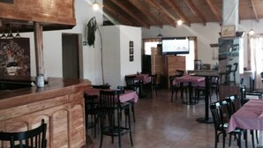 A spacious restaurant with wooden beams, a bar area, and multiple tables and chairs. - ElMaima Hotel (Veintiocho de Noviembre)