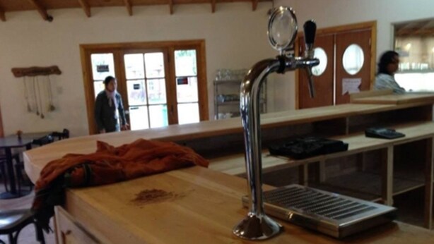 A bar area with a wooden counter, a metal faucet, and a window with a view. - ElMaima Hotel (Veintiocho de Noviembre)