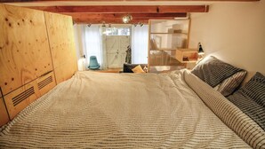 A bedroom with a large bed, wooden wardrobe, and a small desk with a lamp. - 1 bedroom beach front home in Enkhuizen (Enkhuizen)