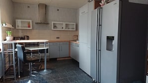 A compact kitchen with a refrigerator, a sink, and a dining area with a table and chairs.