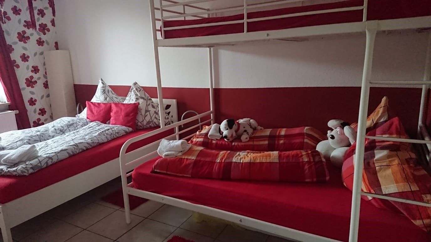 A bunk bed room with two beds, each with red bedding and pillows.