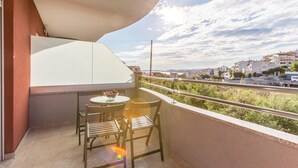 A balcony with a table and chairs, a bowl of fruit, and a view of a town and mountains. - Cozy apartment in Podstrana (Podstrana)
