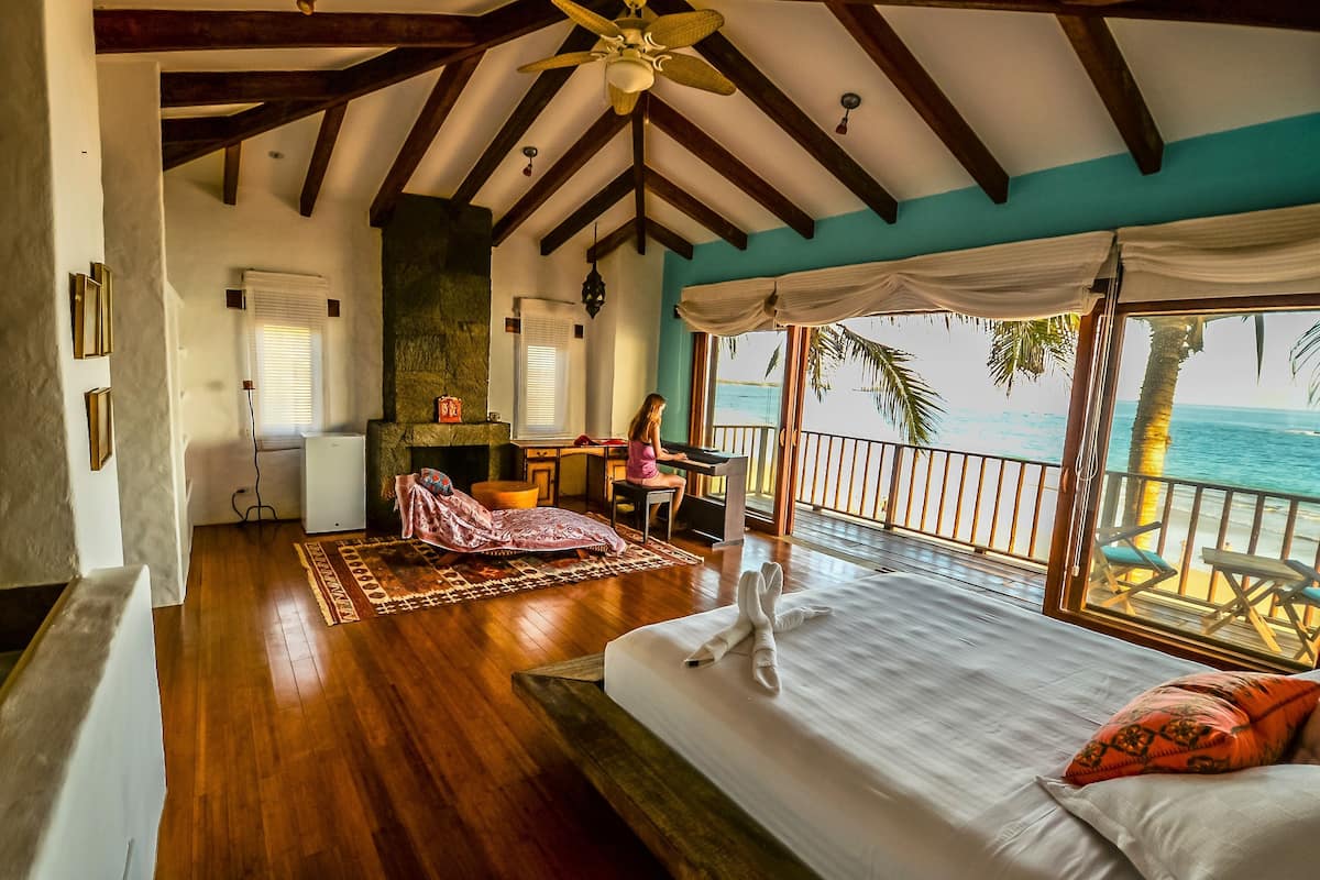 Una habitación amplia con una cama grande, un escritorio y vista al océano.
