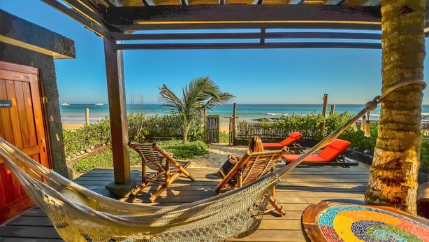 A hammock on a wooden deck with a view of the beach and ocean. - Casa Baronesa (Puerto Villamil)