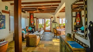 A spacious living area with a wooden ceiling, a dining table, and a sofa. - Casa Baronesa (Puerto Villamil)