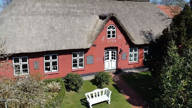 A traditional red house with a thatched roof and a white bench in front. - Old school ("Godewind" from "Gegen den Wind") Sankt Peter Ording village - studio (St. Peter-Ording)