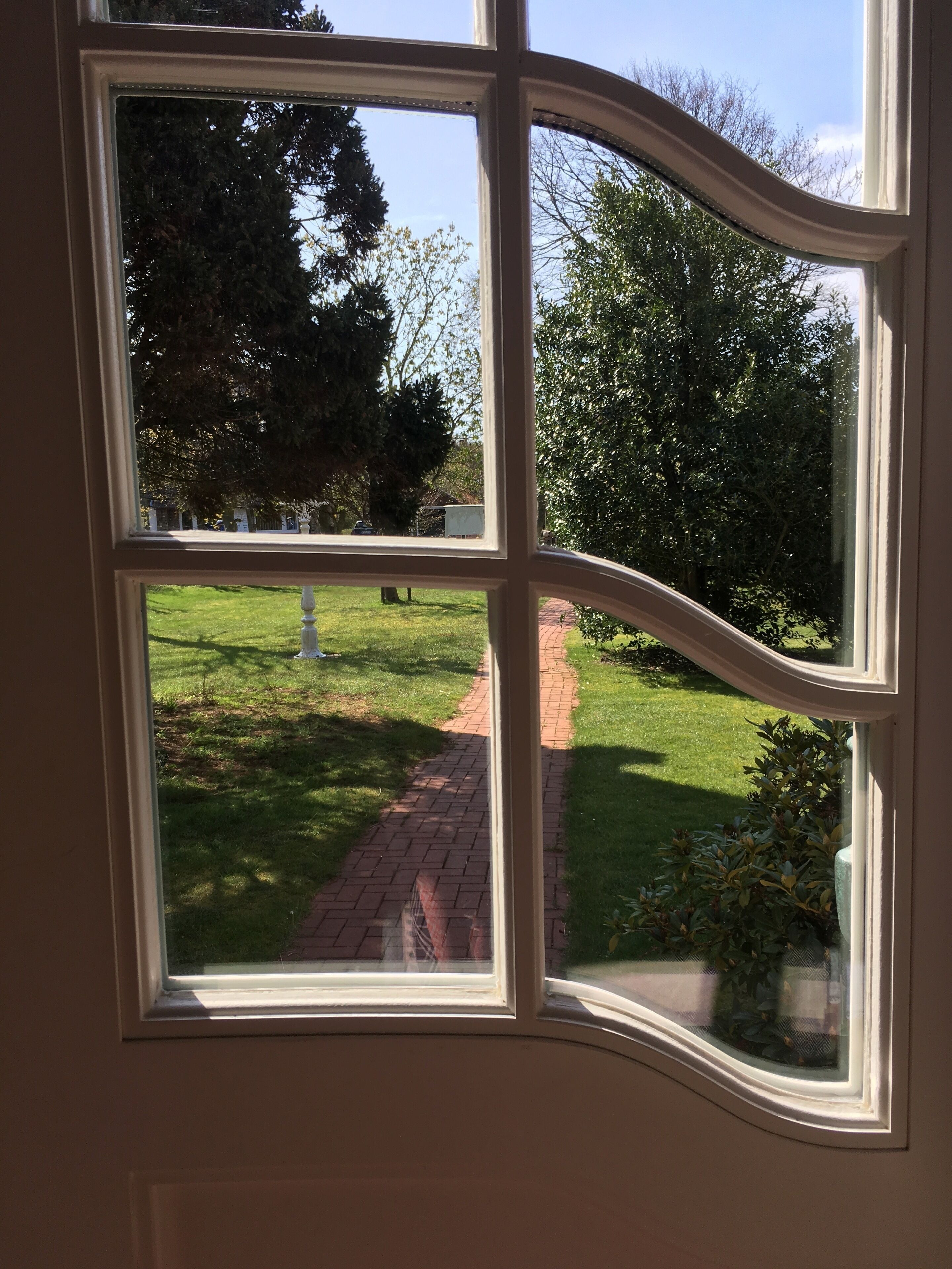 Una ventana con vista a un área verde y un sendero de ladrillo.