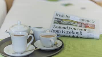 Ein Tablett mit Kaffeetassen und einem Teekessel auf einem Tisch, im Hintergrund eine Zeitung mit der Überschrift 'Irish Independent'.