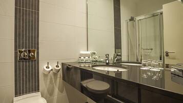 A modern bathroom with a large mirror, a sink, a toilet, and a shower area.