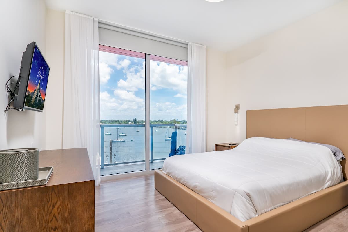 Une chambre d’hôtel avec un lit, un bureau, une télévision et une vue sur la mer.