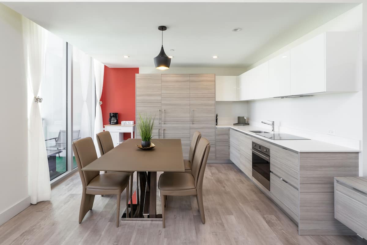 Une cuisine moderne avec des meubles blancs, un îlot central et un coin repas comprenant une table et des chaises.