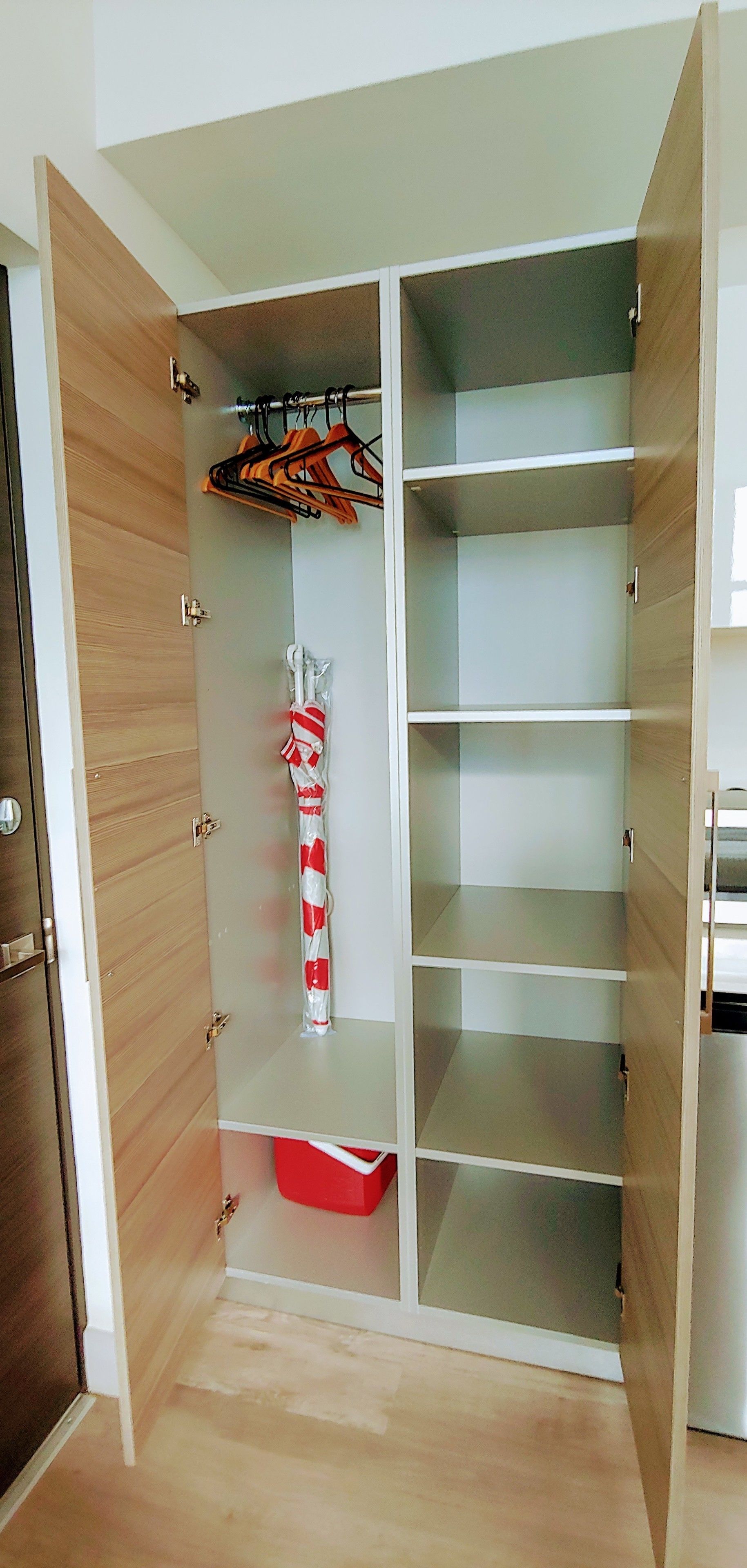 A walk-in closet with wooden doors, multiple shelves, and a red storage bin.