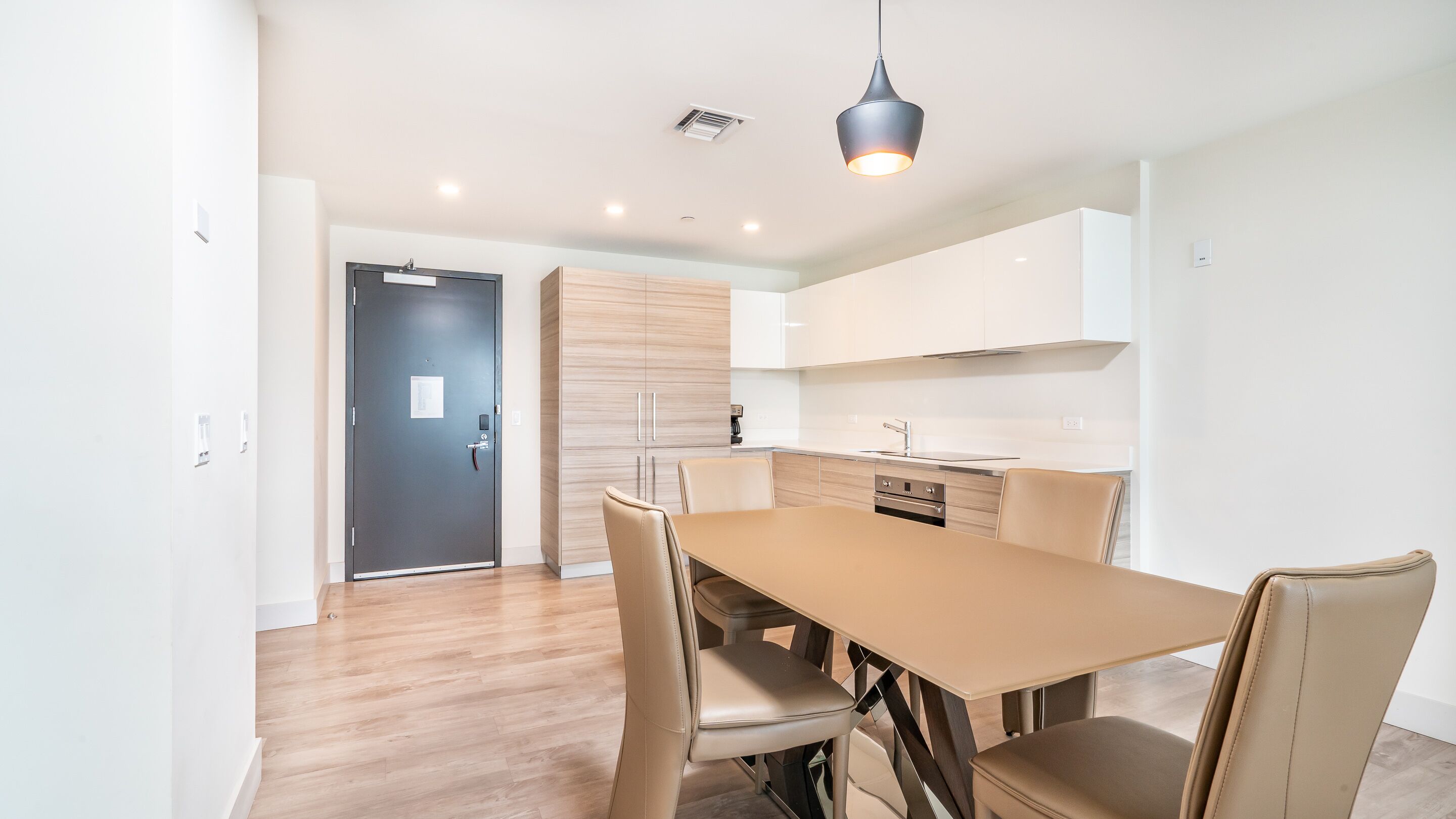 A modern kitchen with white cabinets, a stainless steel stove, and a black pendant light.