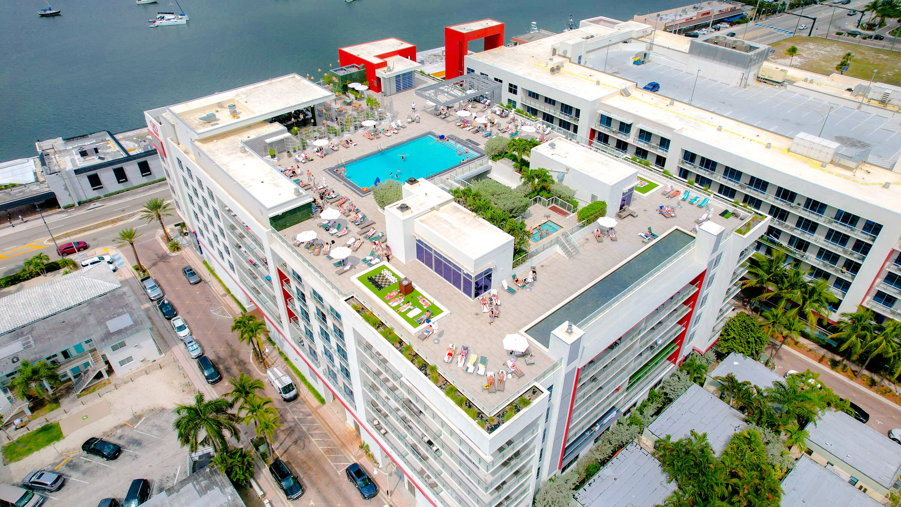 Un edificio alto con piscina sul tetto, numerosi balconi e vista sul mare.