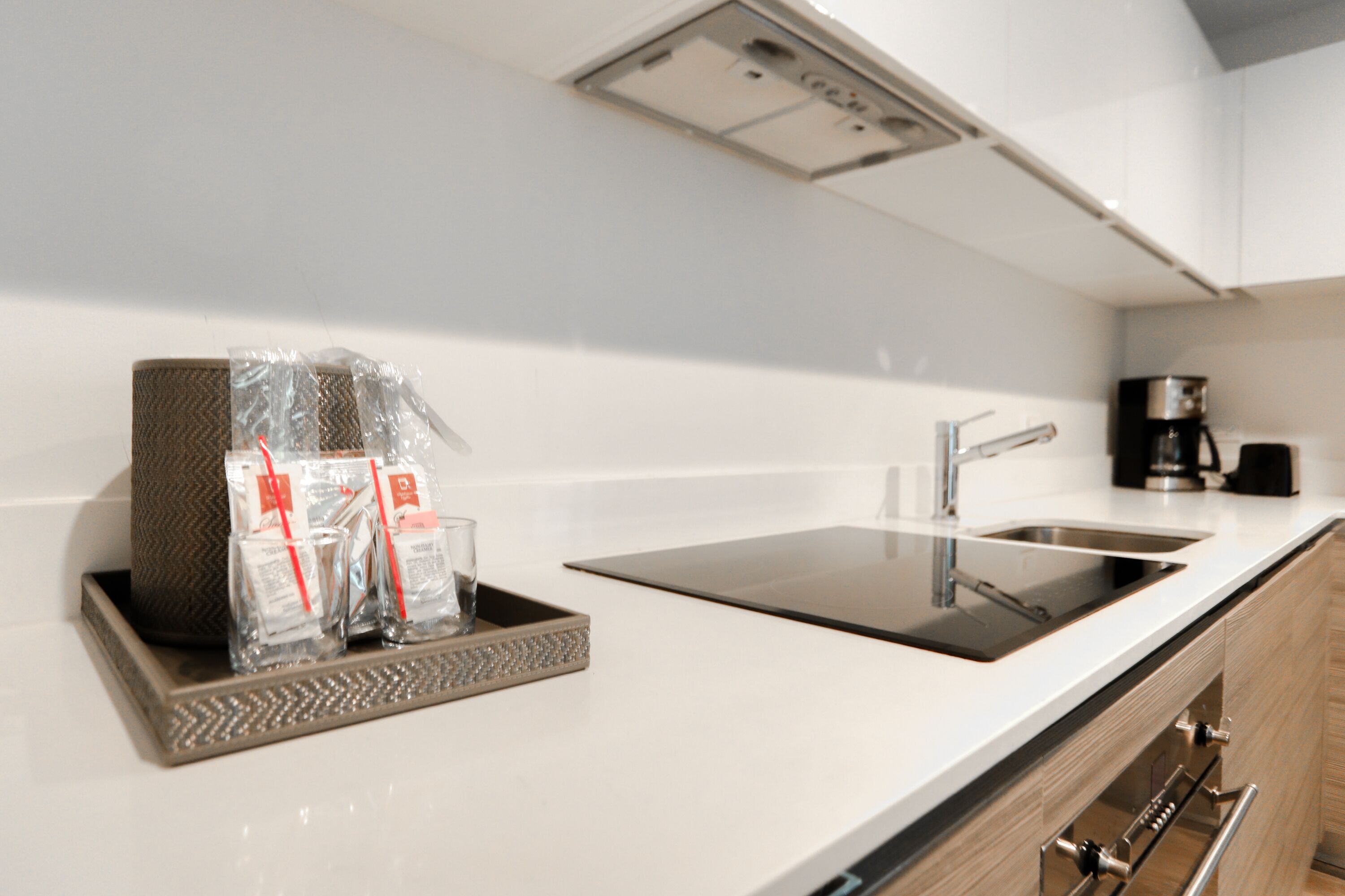 A modern kitchen with a built-in dishwasher, a stainless steel sink, and a coffee maker.
