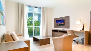 Een moderne hotelkamer met een groot raam, een flatscreen televisie, een bureau, een stoel en een bank.
