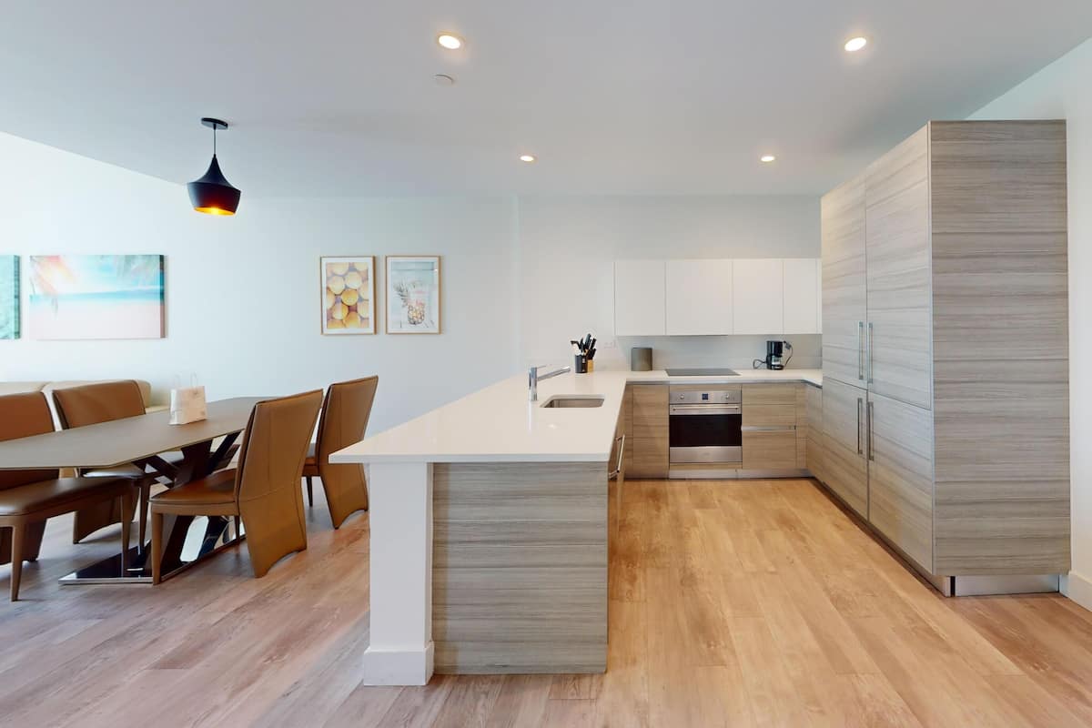 Une cuisine moderne dotée d’un îlot central, de meubles en bois et d’un coin repas avec une table et des chaises.