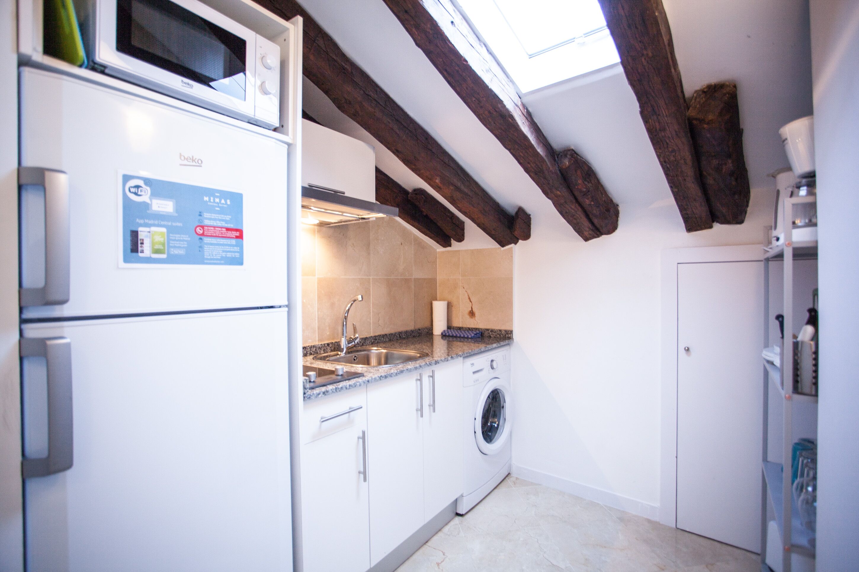 A compact kitchen with a built-in microwave, a washing machine, and a sink.