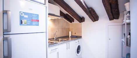 A compact kitchen with a built-in microwave, a washing machine, and a sink.