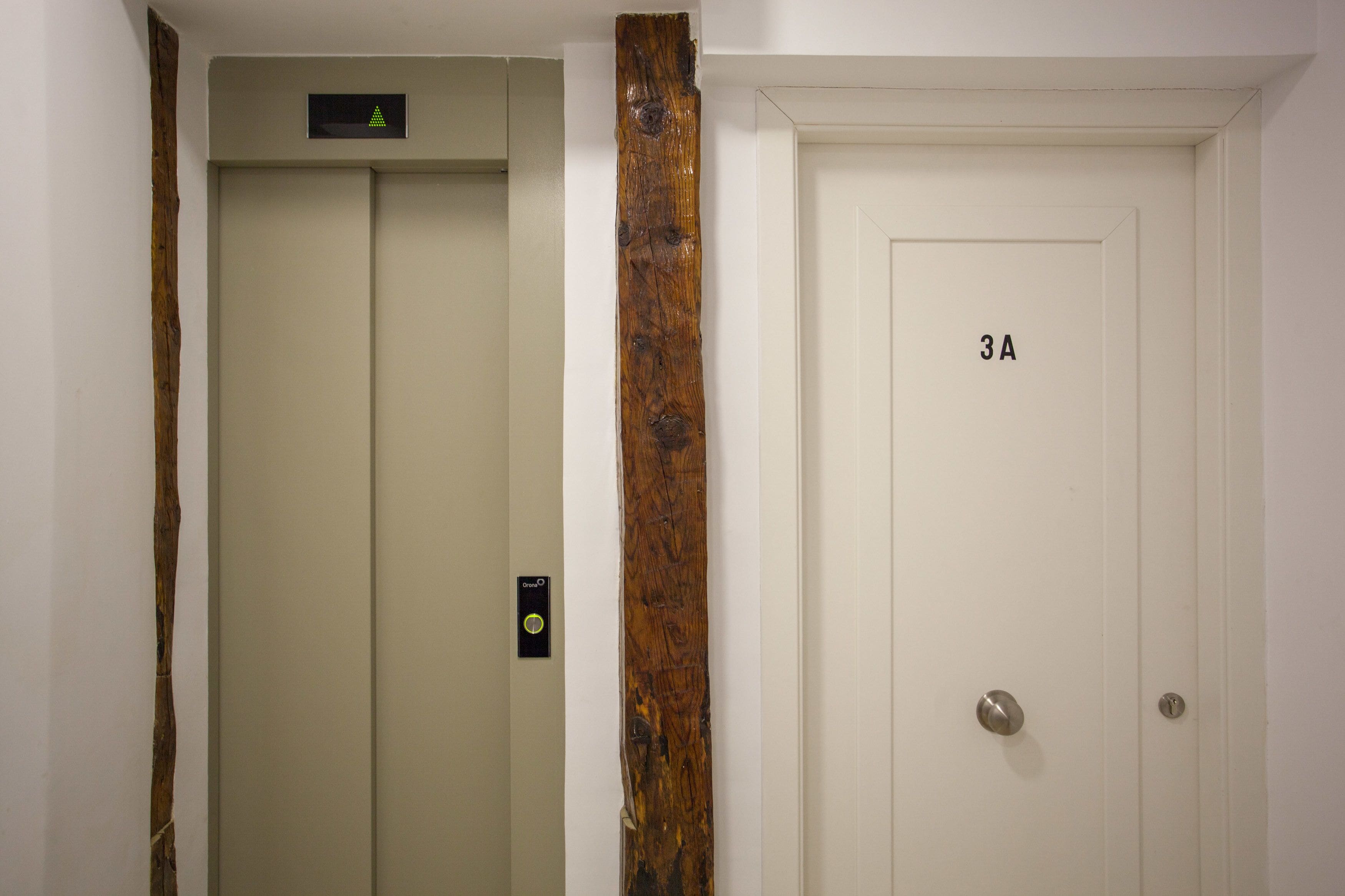 A white door with the number 3A, a wooden accent, and a small electronic device on the wall.