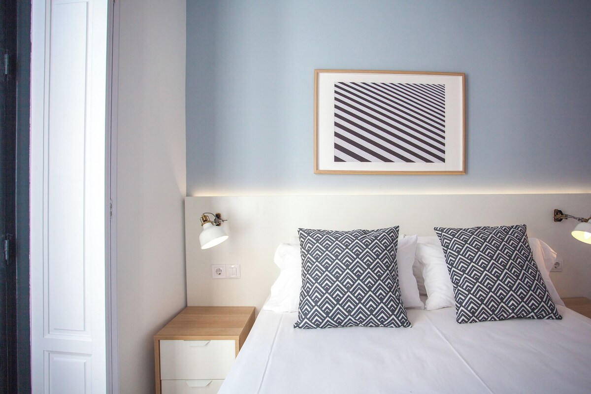 A neatly arranged bedroom with a bed, two bedside tables, and a wall-mounted picture frame.