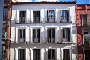 A multi-story building with balconies, white and red facades, and shutters on windows. - Gran Central Suites (Madrid)