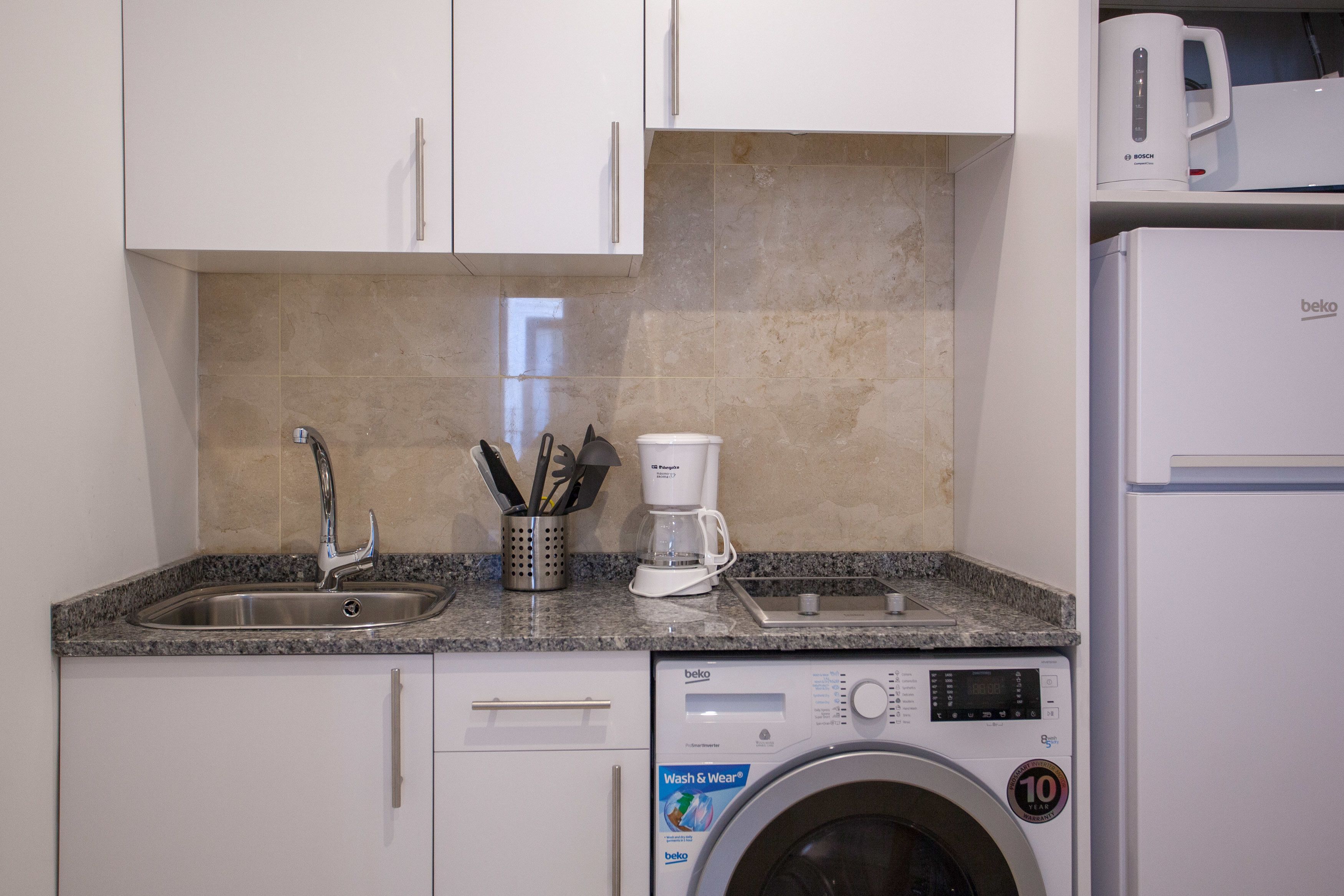 A kitchen with a built-in washing machine, a coffee maker, and a microwave.