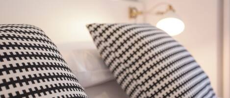 Primer plano de una cama con almohadas de estampado blanco y negro.