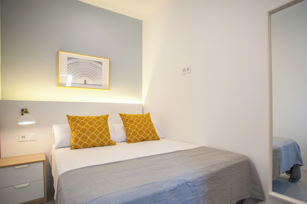 A neatly arranged bedroom with a bed, bedside table, and a wall-mounted picture.