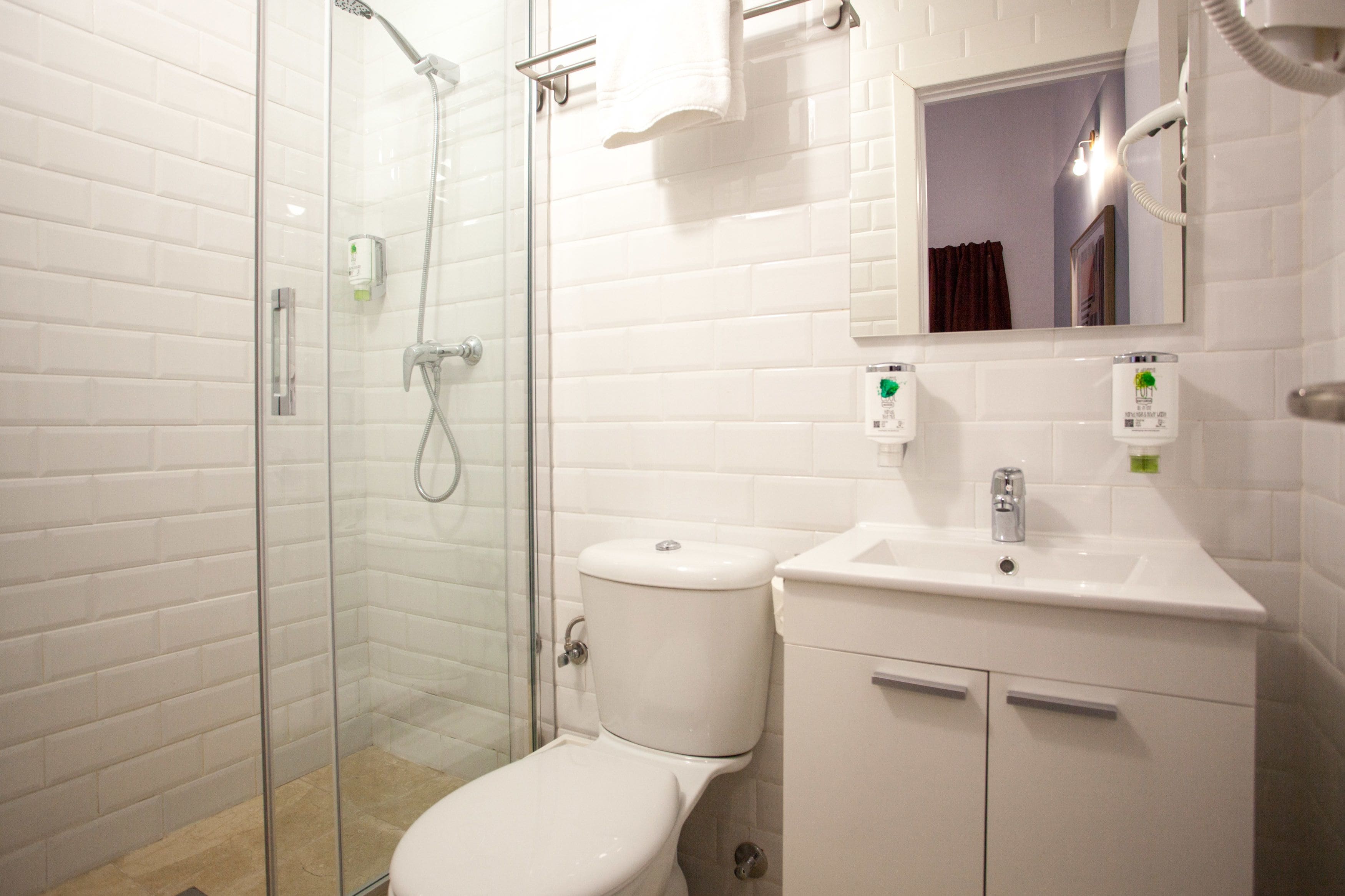 A modern bathroom with a glass-enclosed shower, a white toilet, and a sink with a mirror above it.