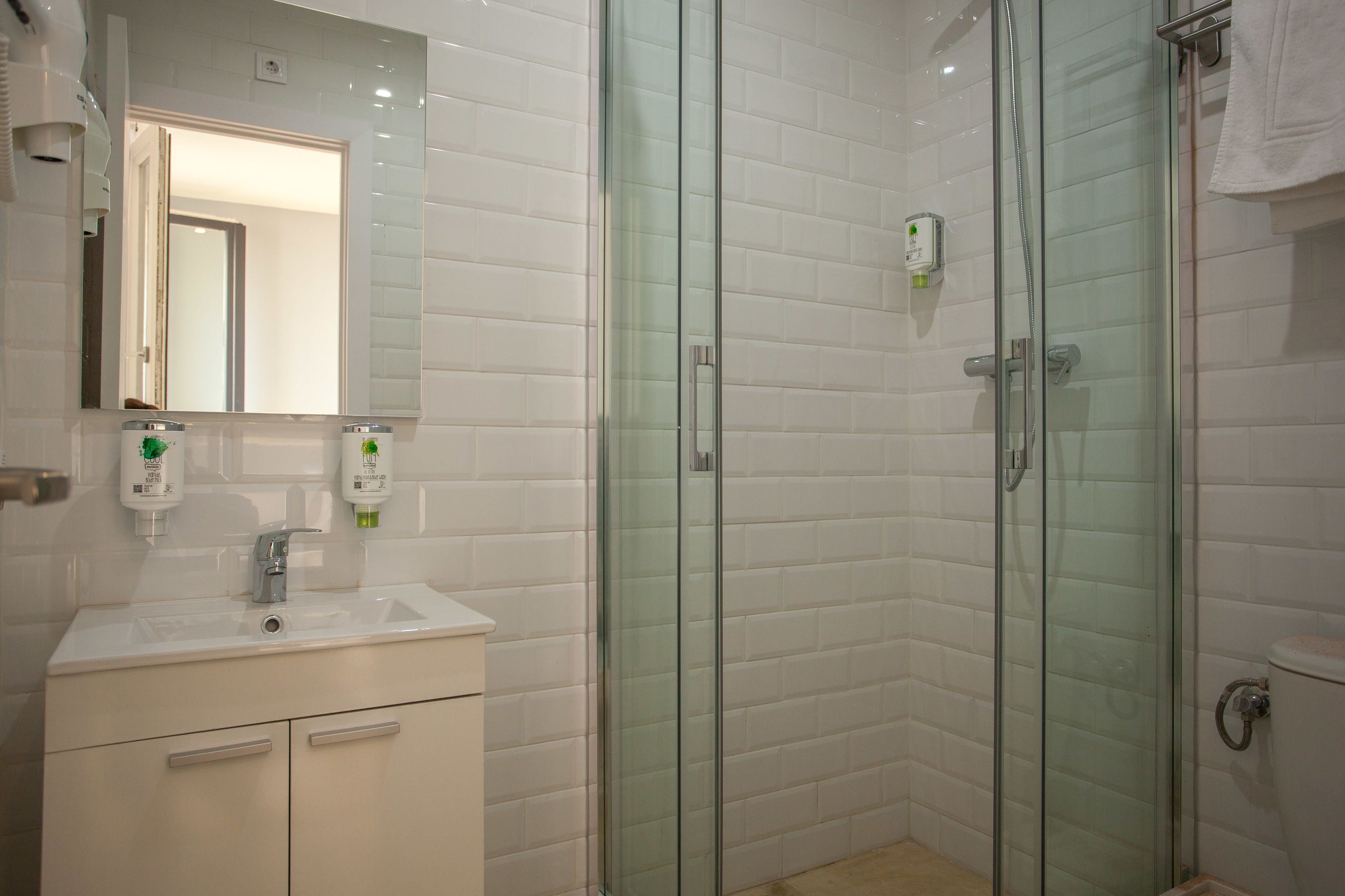 A modern bathroom with a glass-enclosed shower, a white sink, and a mirror above the vanity.