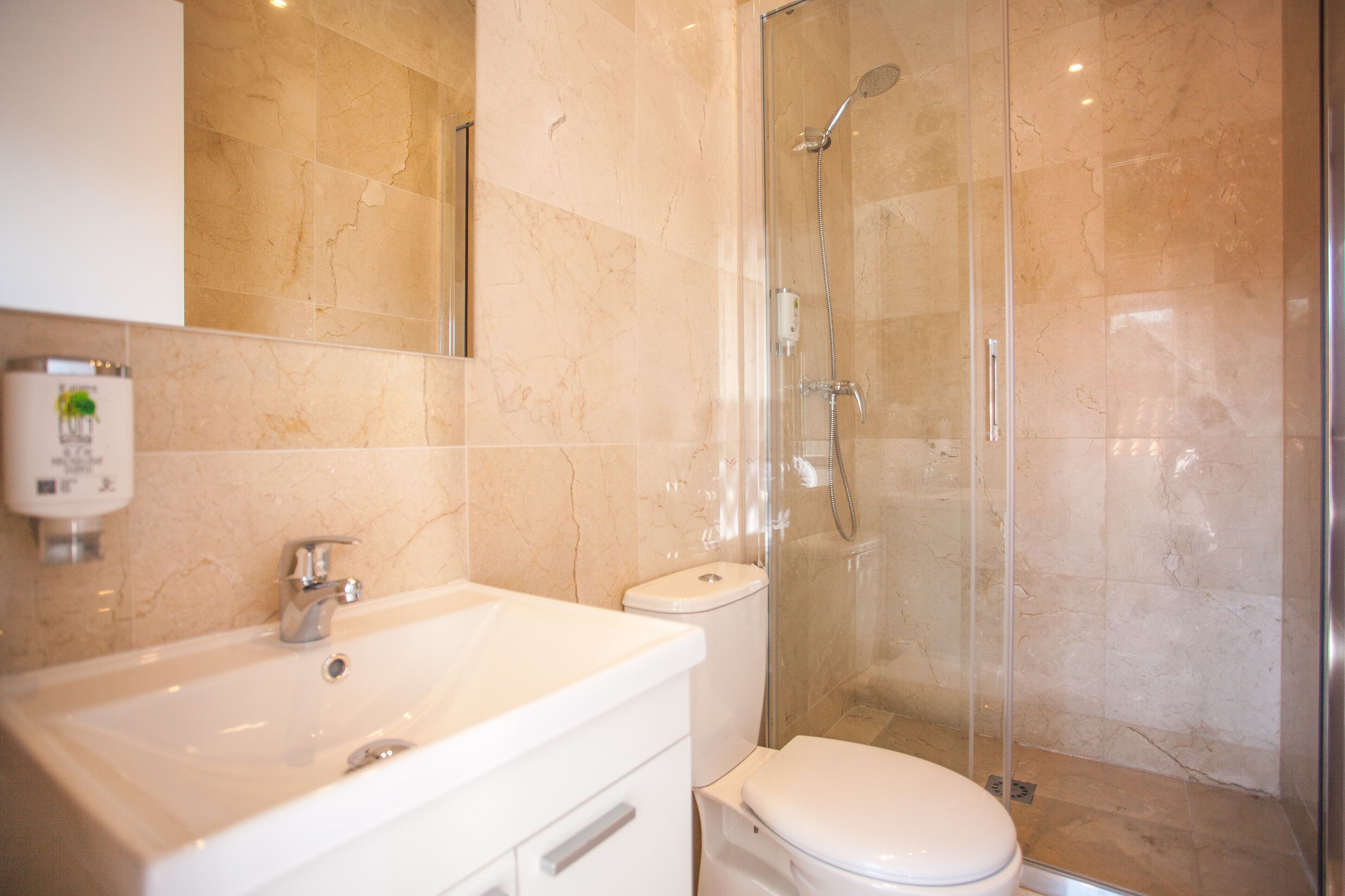 A bathroom with a white sink, toilet, and glass-enclosed shower.