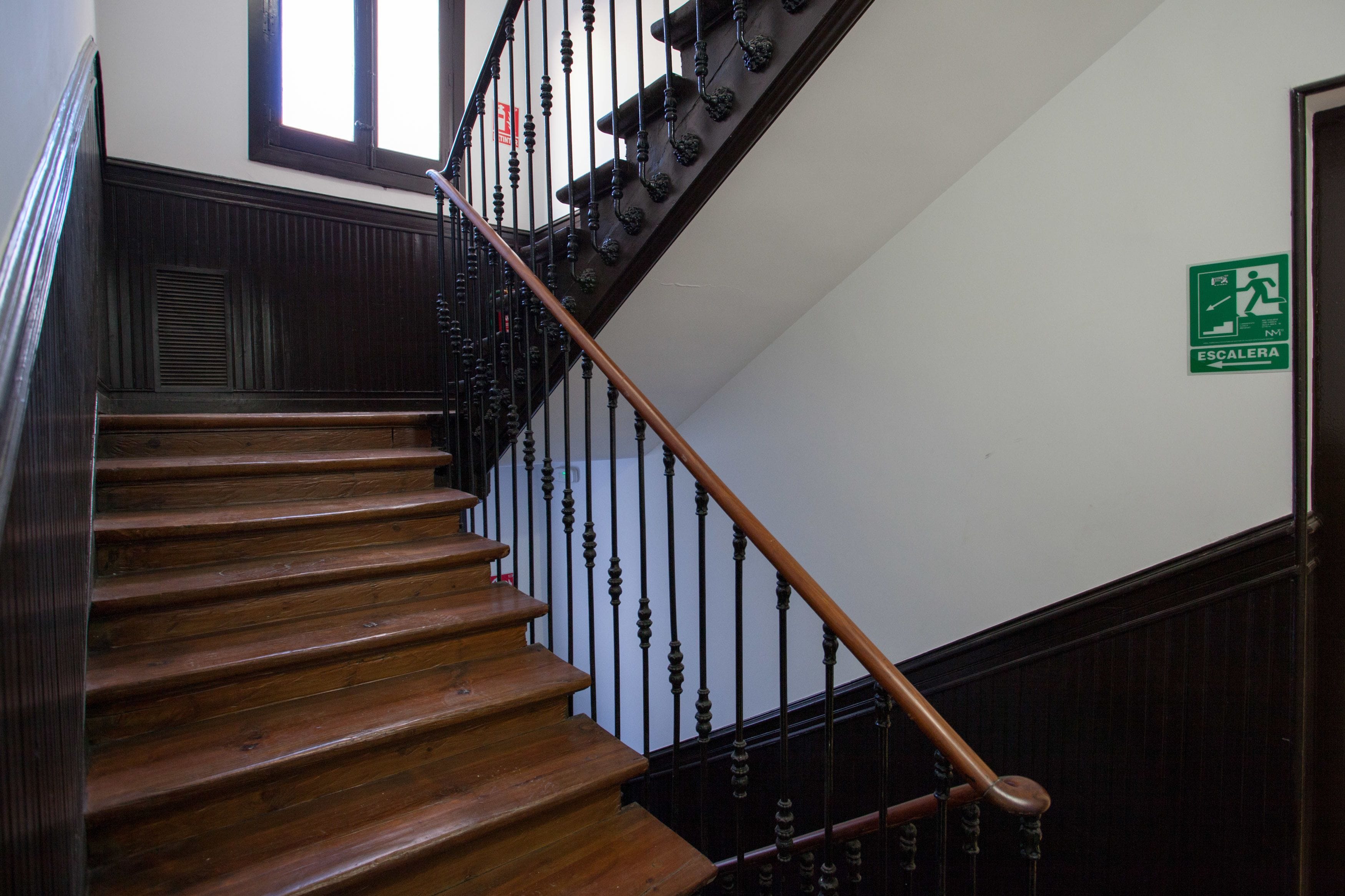 A wooden staircase with black balusters and a wooden handrail.