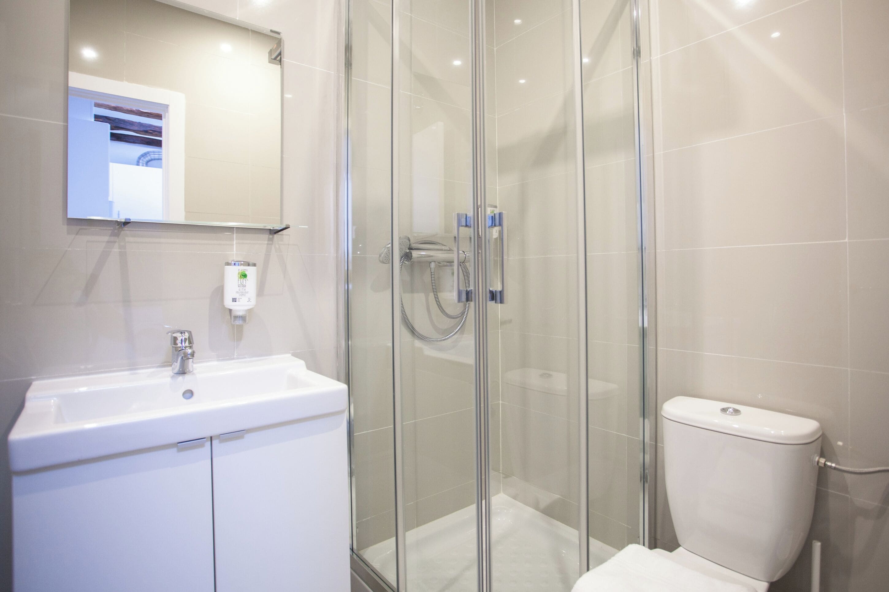 A modern bathroom with a glass-enclosed shower, a white sink, and a toilet.