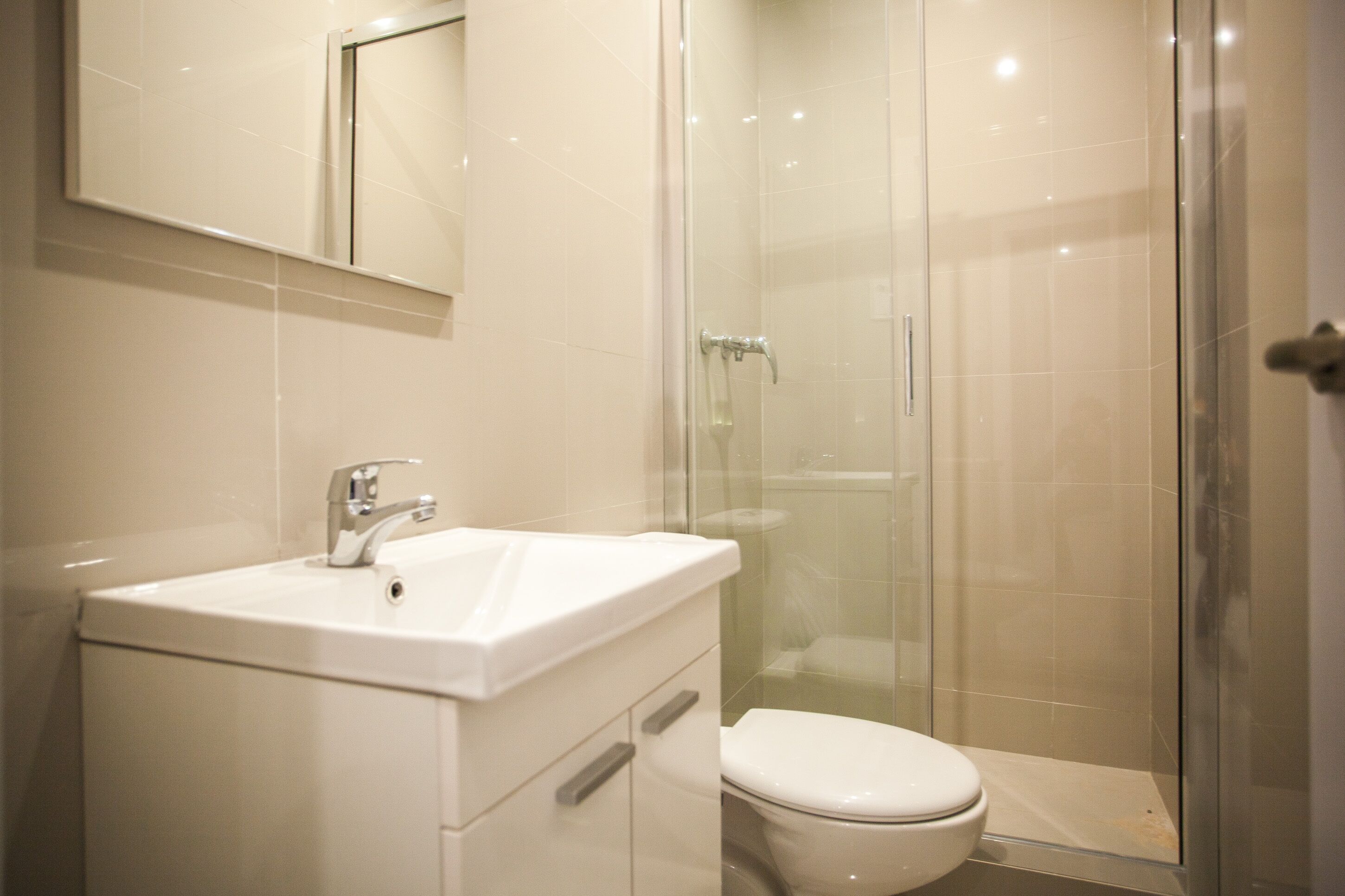 A modern bathroom with a glass-enclosed shower, a white sink, and a toilet.