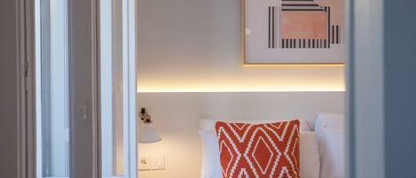 Una habitación de hotel con cama, mesita de noche, lámpara y una obra de arte colgada en la pared.