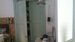 A kitchen with a dining table, chairs, a stove, and a cabinet. - Persefonis view house (Skopelos)